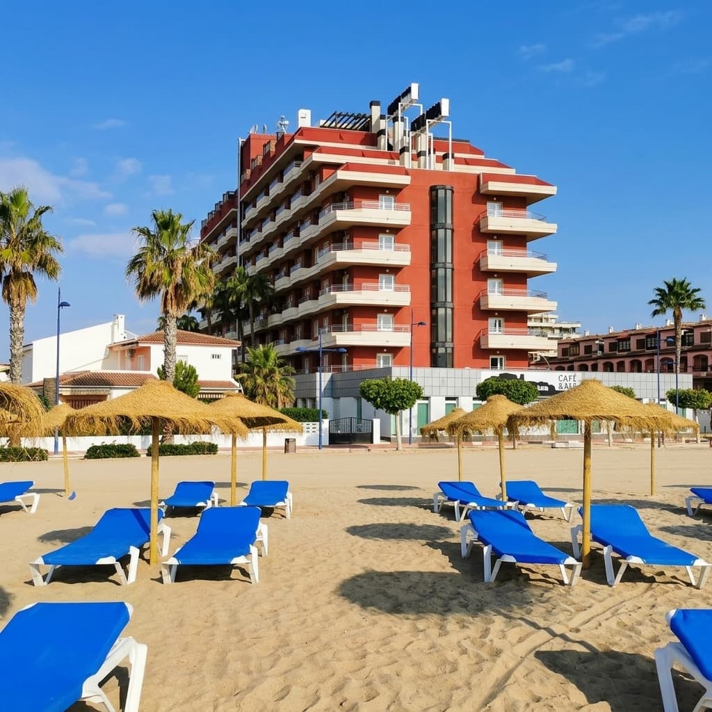Aparthotel Acualandia Peñíscola en primera línea de playa con tumbonas y sombrillas en la arena