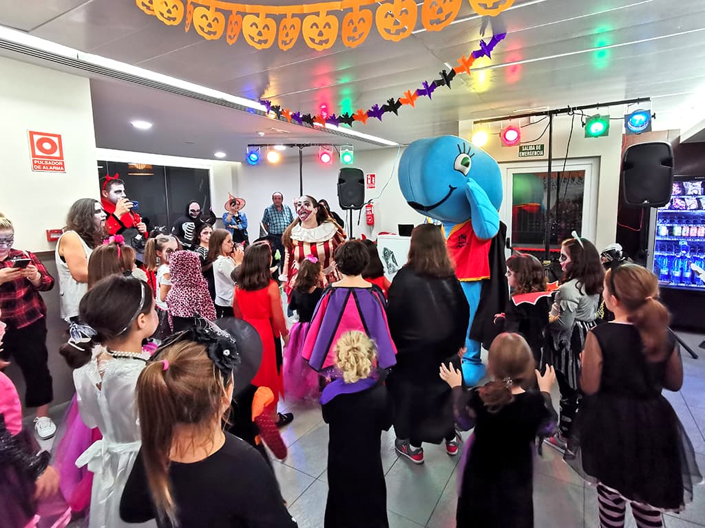 Niños y animadores disfrazados bailando, mascota Ballenita, decoración calabazas