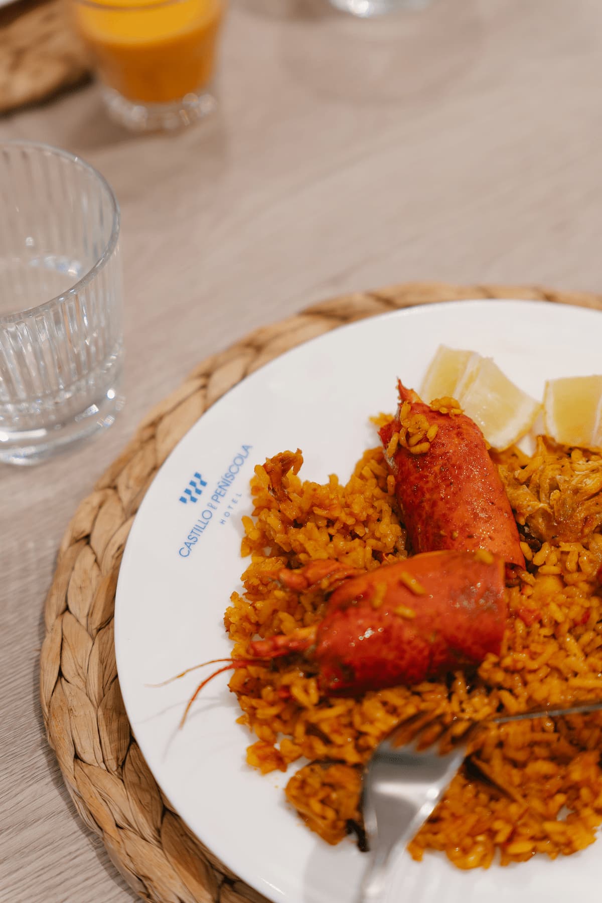 Paella con bogavante servido en plato del Hotel Castillo de Peñíscola sobre mantel de fibra natural