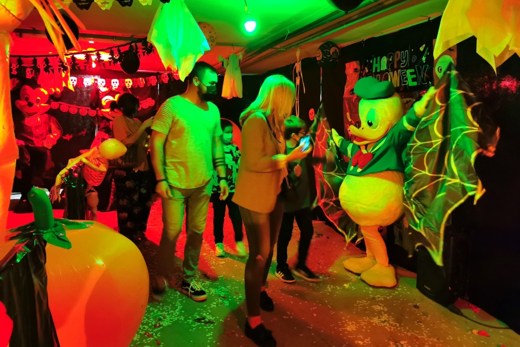 Fiesta disco de Halloween con familias bailando disfrazadas y decoración de luces de neón en Acuazul