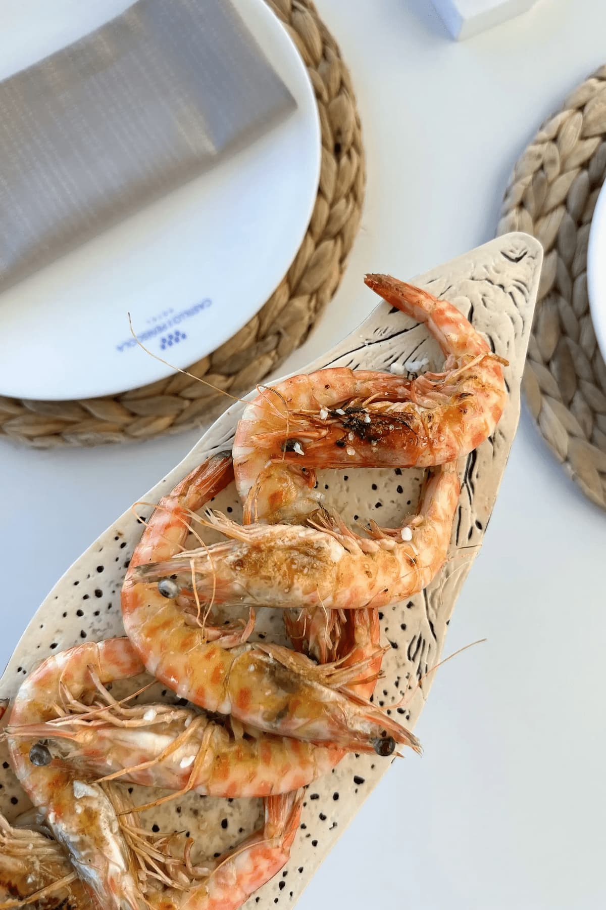 Tapa de gambas a la plancha con sal sobre fuente artesanal de cerámica en el restaurante del hotel