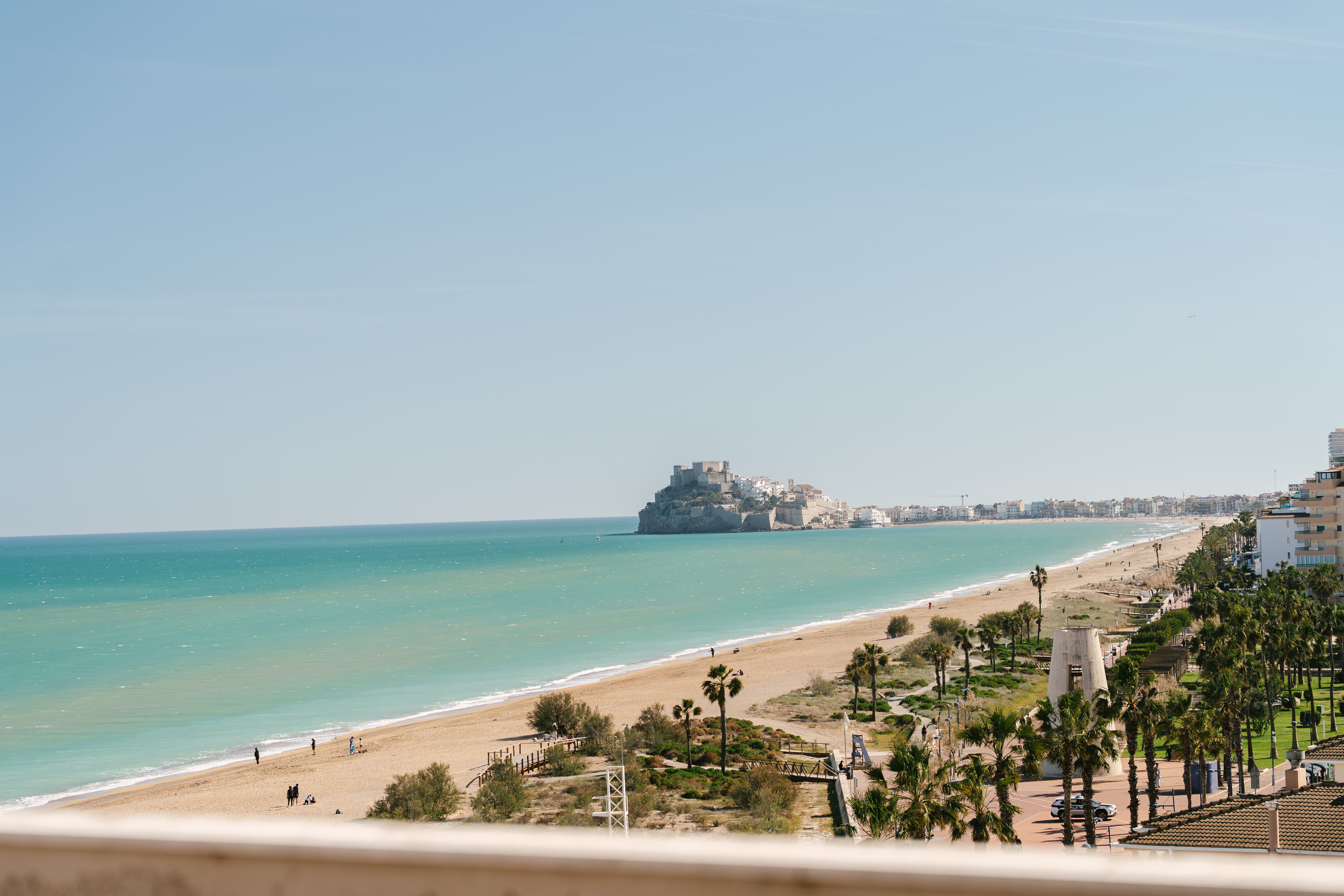 La playa de Peñíscola vista desde una terraza en altura del Aparthotel Acualandia, con el mar turquesa y el Castillo del Papa Luna centrado en el horizonte