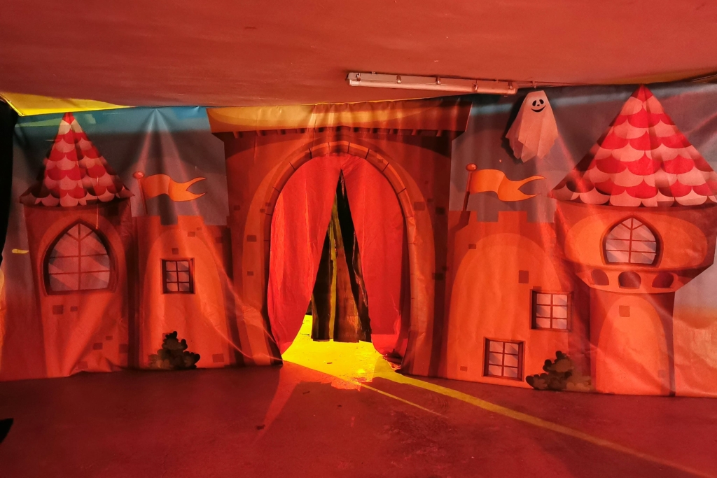 Entrada decorada tipo castillo embrujado con telón rojo y fantasma para el túnel del terror de Halloween en Acuazul