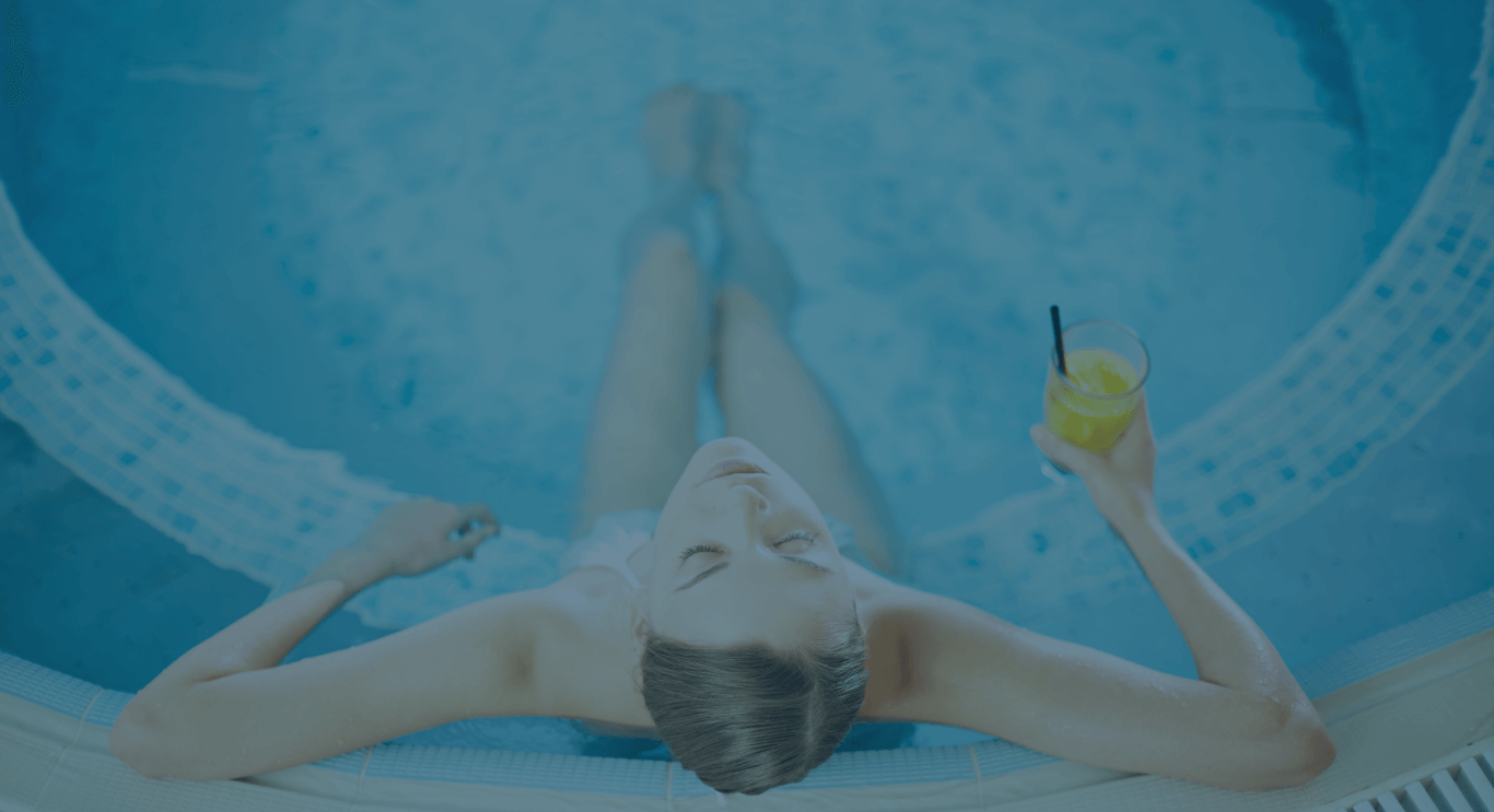 Mujer relajándose en jacuzzi exterior con cóctel en el spa de Hoteles Mediterráneo Peñíscola