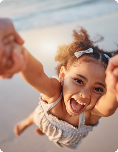 Niña sonriente siendo girada en brazos en la playa de Peñíscola, actividades familiares en Hoteles Mediterráneo