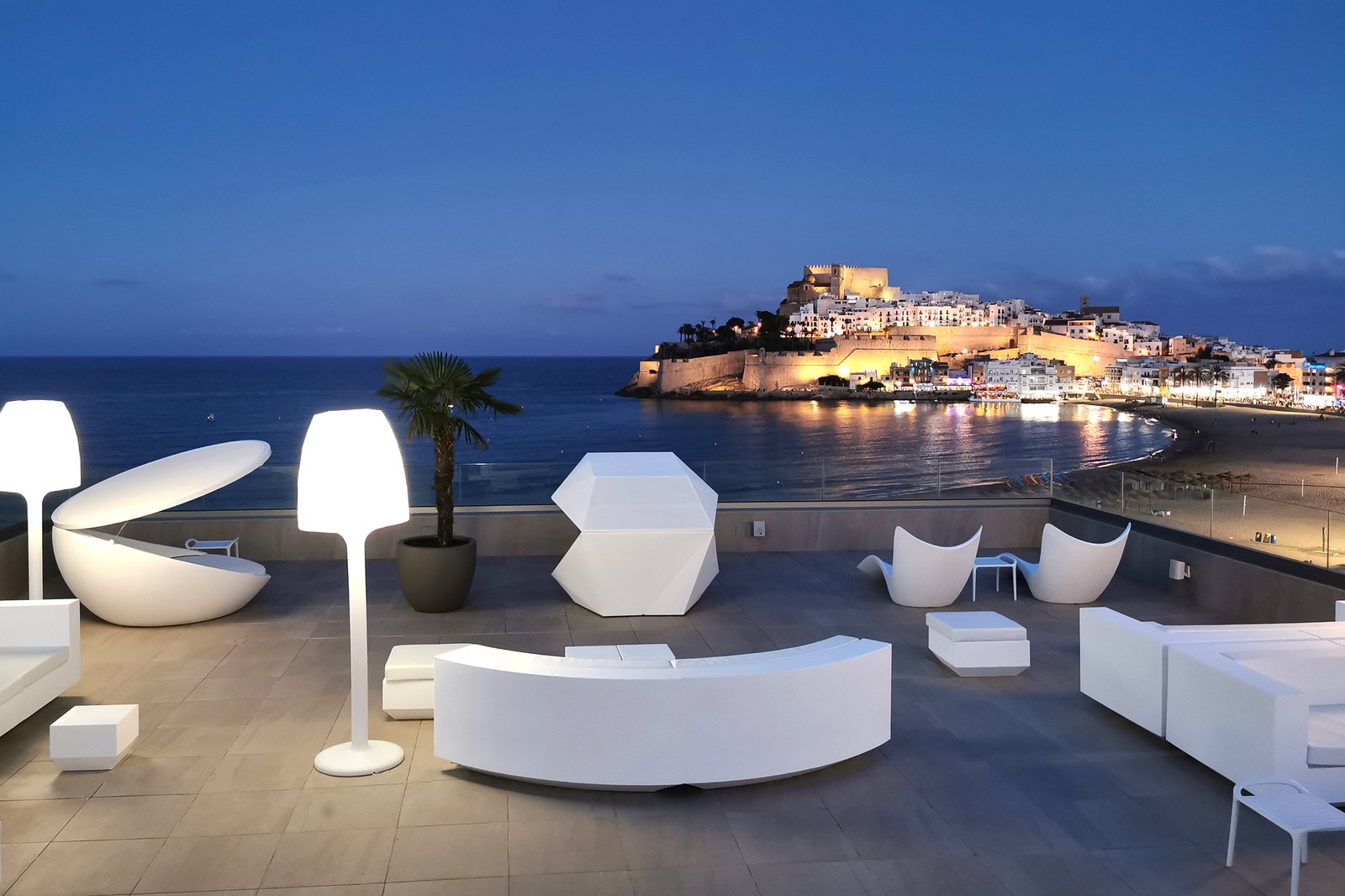 Zona chill out de la terraza Palco al anochecer con el castillo de Peñíscola iluminado