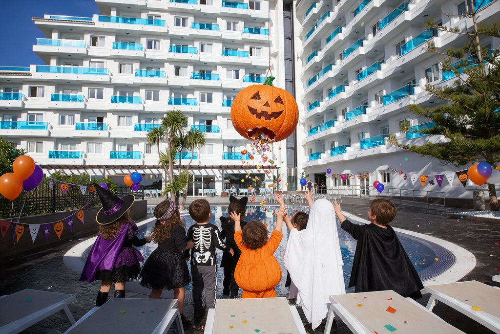 Niños disfrazados de Halloween frente a una piñata de calabaza en la piscina de Acuazul, Peñíscola